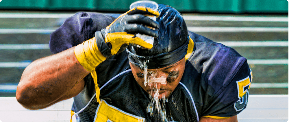 Overheated football player pouring water on his head