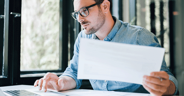 News Insights Man on computer holding paperwork