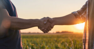 Farmer and Agronomist shaking hands in cornfield